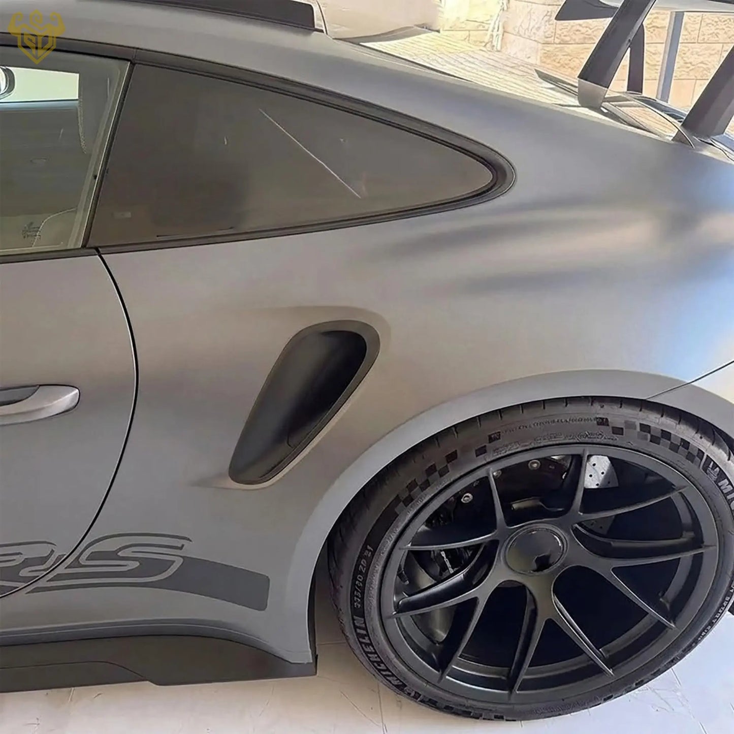 Profile view of a Porsche 992 GT3 RS showing the aerodynamic rear wheel arch vent in matte black.