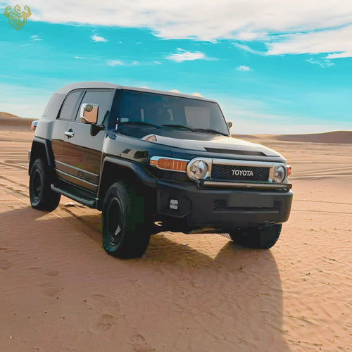  Black Toyota FJ Cruiser equipped with RIGID CUSTOM WORKS bumper light brackets and Osram wide lighting, posed in the Dubai desert landscape, front angle view.